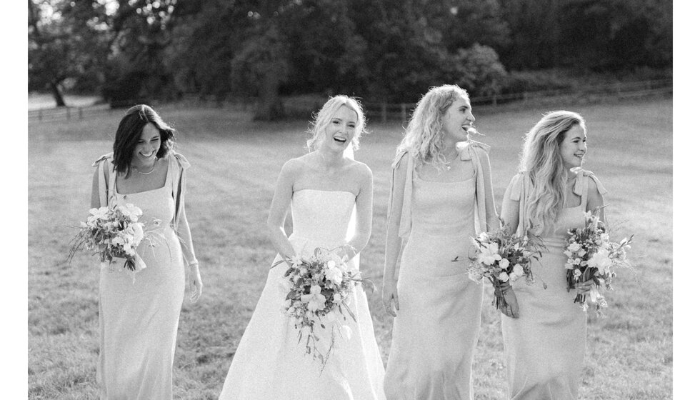 Smiling bride and bridesmaids in Hampshire country house wedding venue garden.